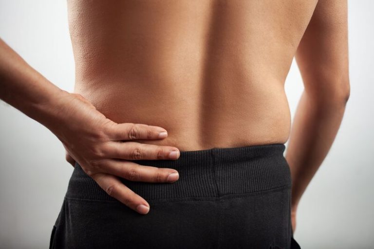 Lower back pain: A person holding their lower back, potentially seeking chiropractic treatment for pain relief.