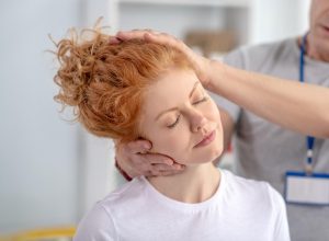Woman receiving chiropractic neck adjustment, eyes closed, during a chiropractic treatment session.