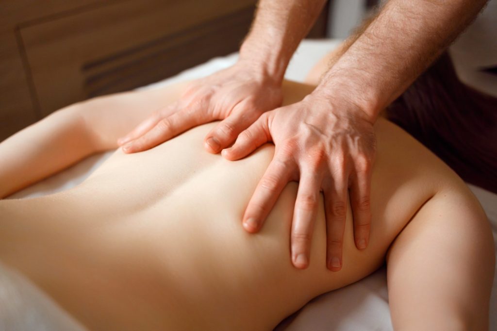 Chiropractor performing spinal manipulation on a female patient, focusing on back pain relief and improved posture.
