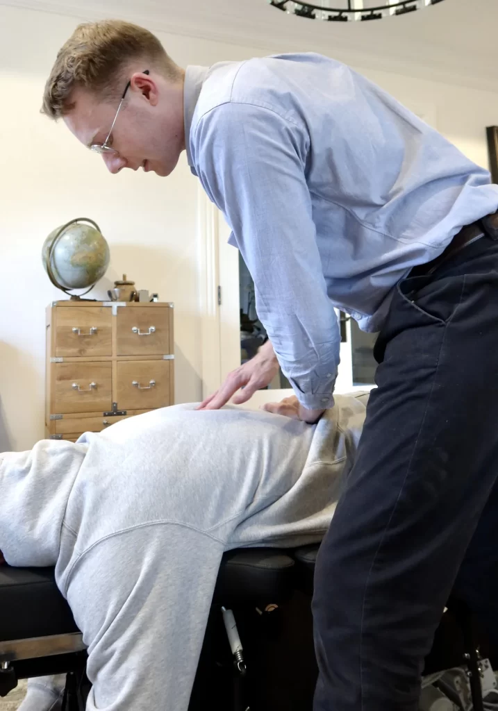 Chiropractor adjusting patient's back, providing chiropractic treatment for spinal alignment and pain relief.