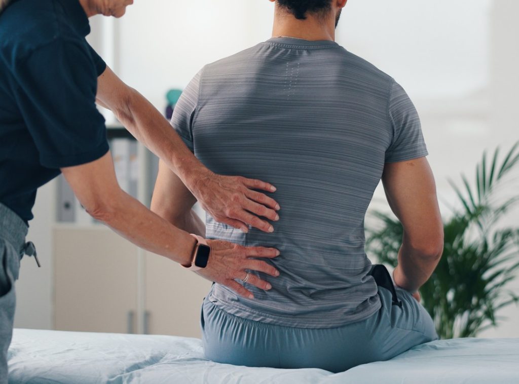 Chiropractor examining patient's lower back for spinal alignment and pain relief during a chiropractic treatment session.