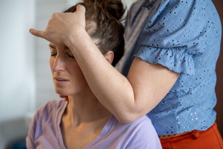 Chiropractor performing a muscle test on a female patient's forehead during a chiropractic examination.