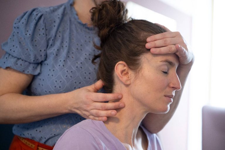 Chiropractor performing a neck and head adjustment on a female patient with eyes closed, promoting relaxation and pain relief.