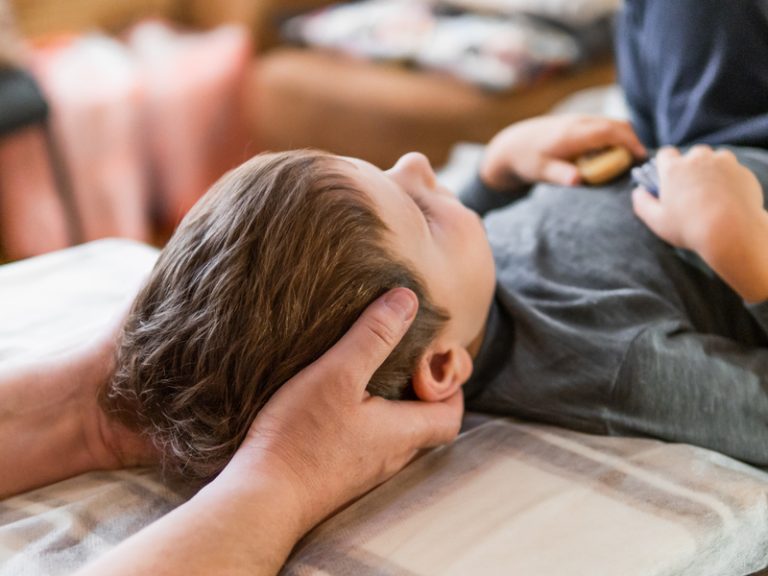 Child receiving chiropractic treatment, doctor adjusting neck for pediatric care.