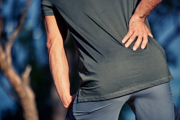Man experiencing lower back pain, possibly needing chiropractic treatment for spinal alignment and pain relief.