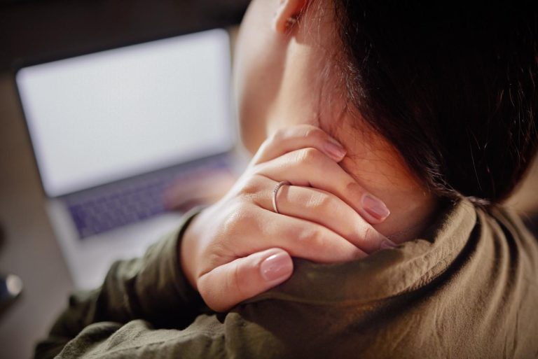 Woman experiencing neck pain from computer use, potentially needing chiropractic care.