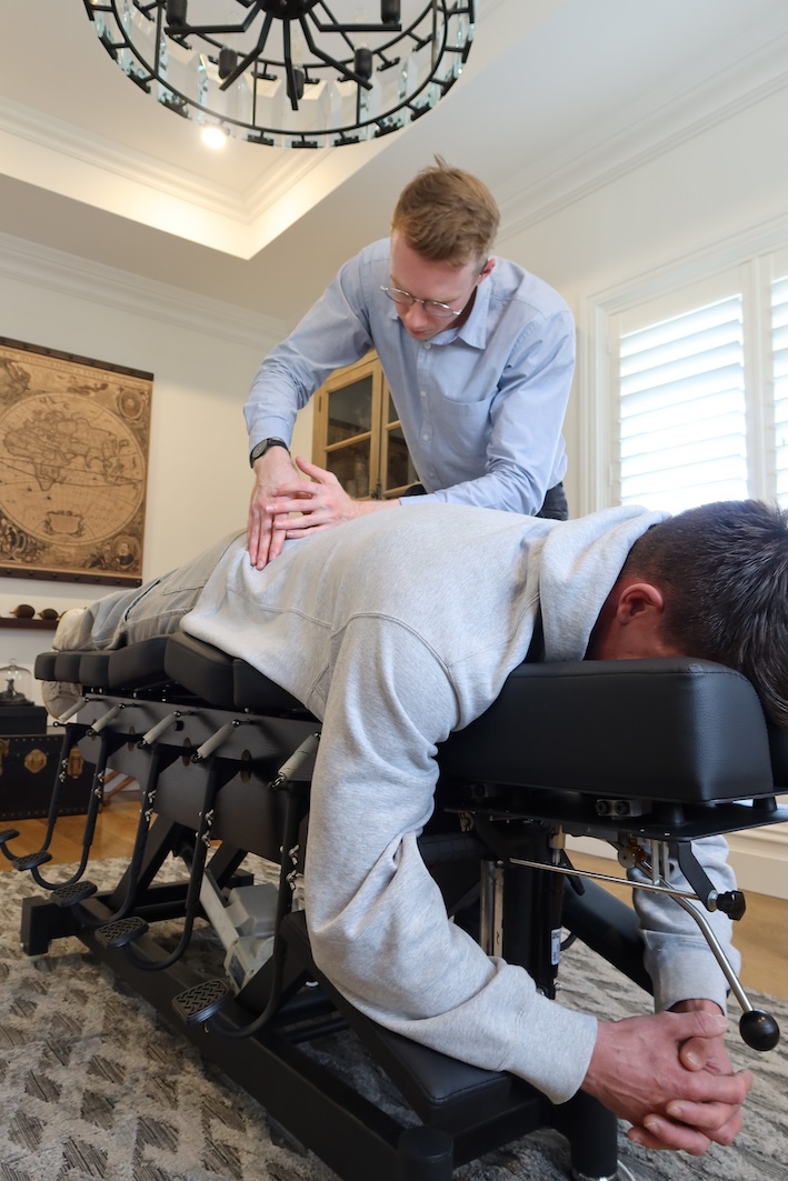 Dr Kyle Duncan Chiropractor adjusting a patient's back on a specialized chiropractic table for spinal alignment.