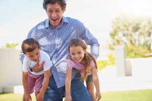 Happy father holding his children, promoting family wellness and chiropractic care for all ages.
