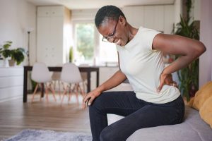 Woman experiencing lower back pain, possibly seeking chiropractic treatment for relief.