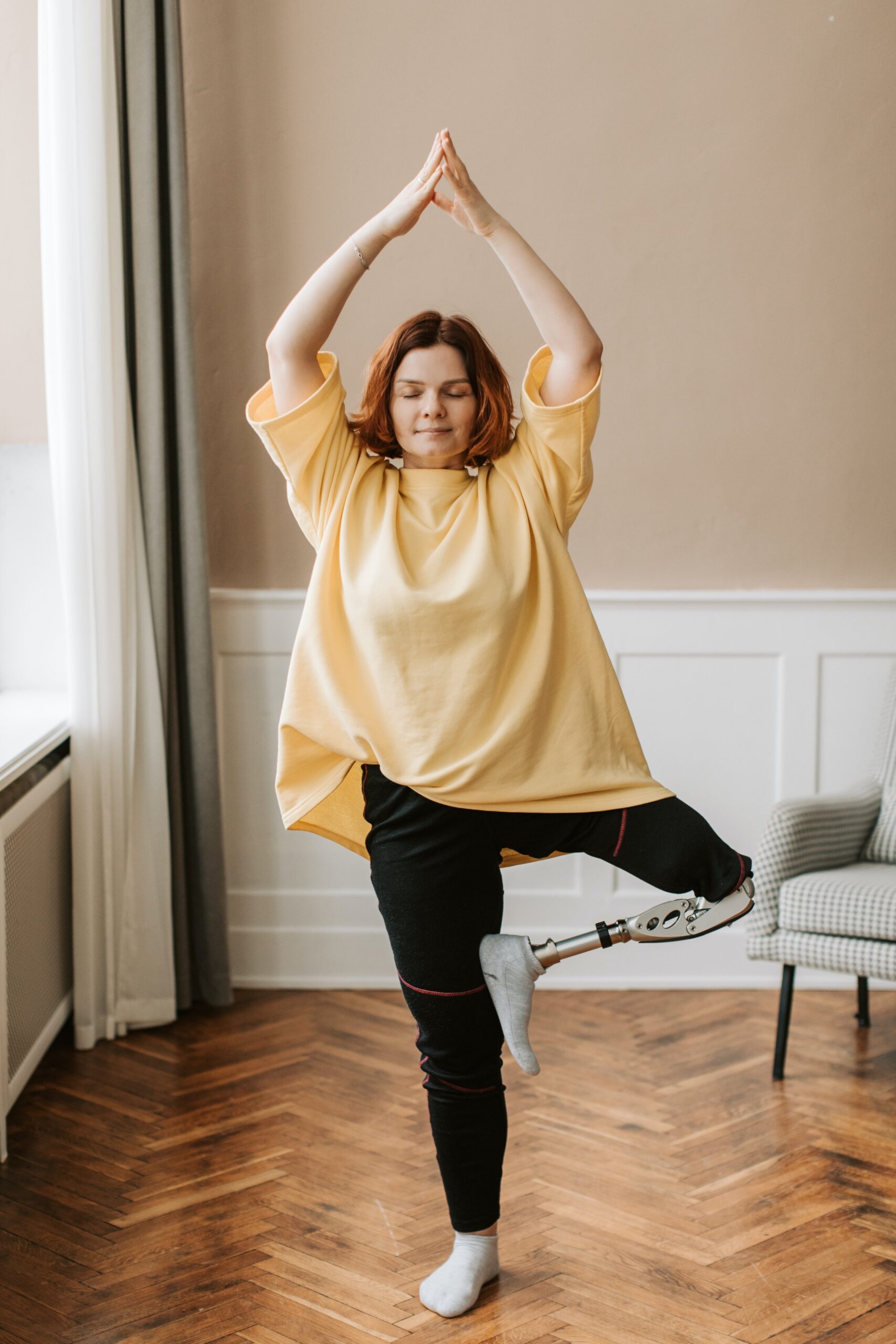 Woman with prosthetic leg practicing yoga, demonstrating flexibility and balance, potentially benefiting from chiropractic care for alignment and mobility.